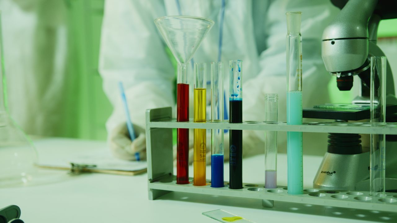 Home Close-up photo of lab research setup with test tubes and a microscope.