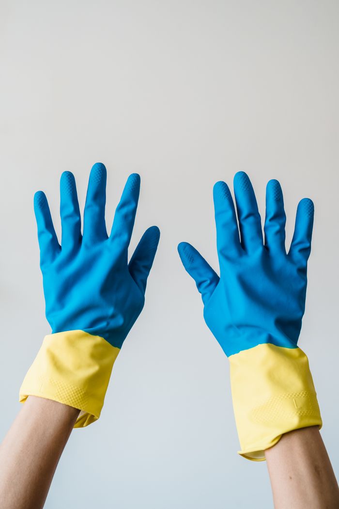 Home Close-up of two hands wearing blue and yellow rubber gloves for protection.